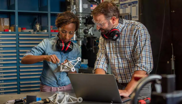 Une personne mesure une pièce qu'une autre modélise en 3D